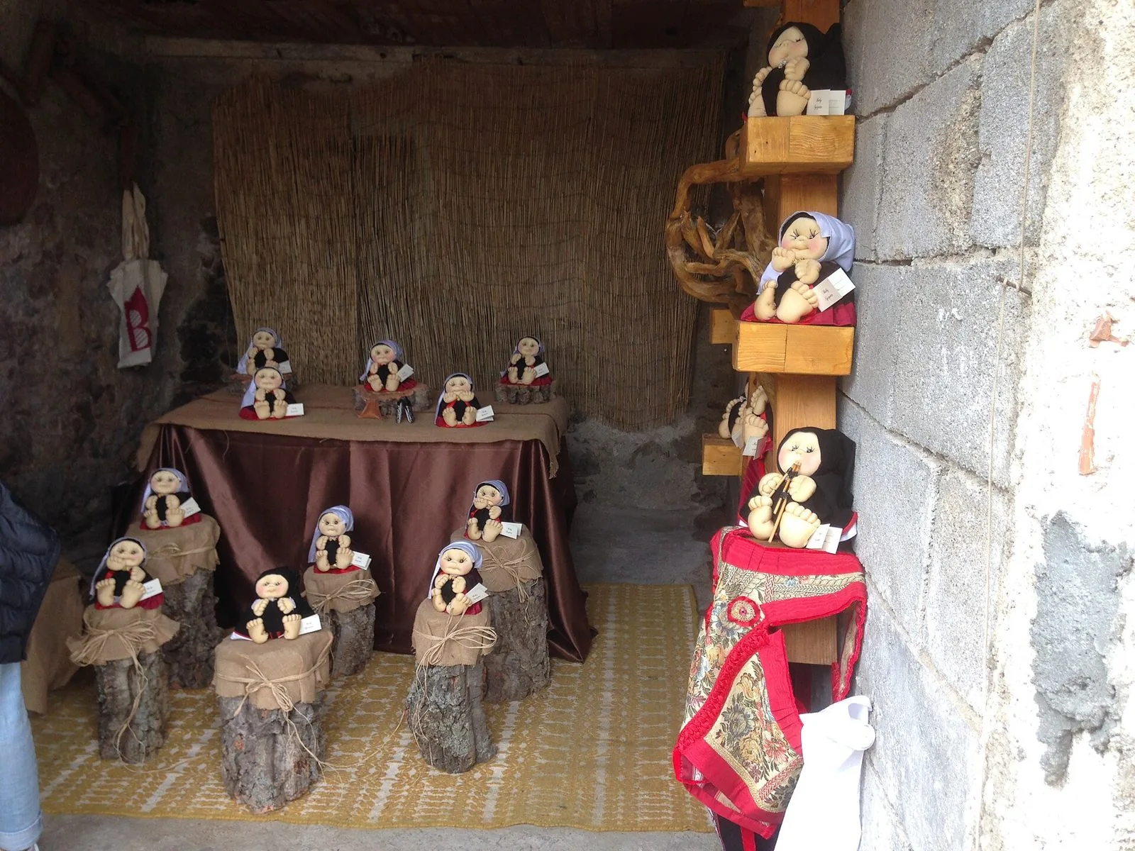Esposizione di bambole artigianali in costume tradizionale in un androne di pietra durante Autunno in Barbagia a Lollove