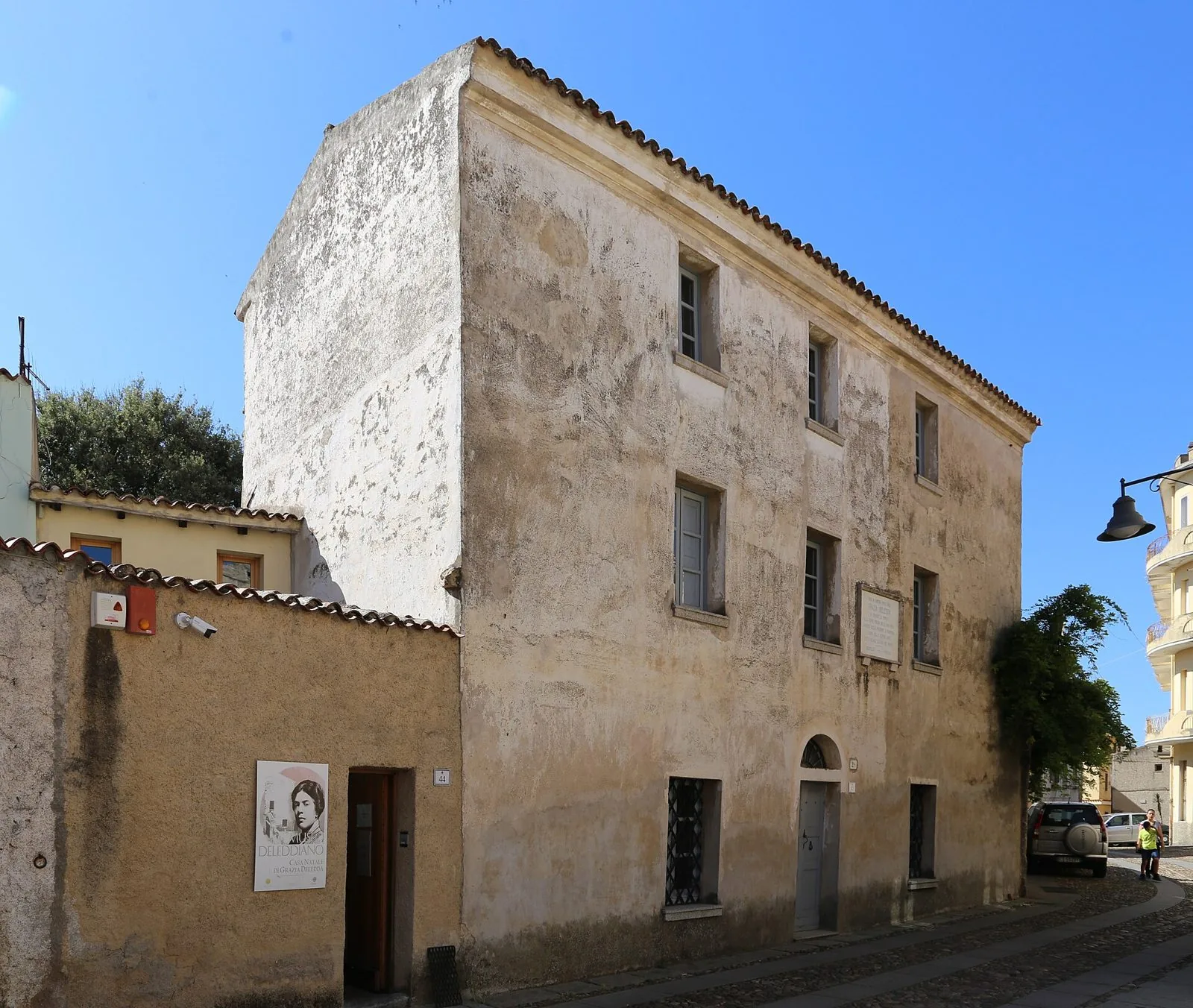 Facciata in pietra della casa natale di Grazia Deledda a Nuoro, oggi Museo Deleddiano, in una via lastricata del centro