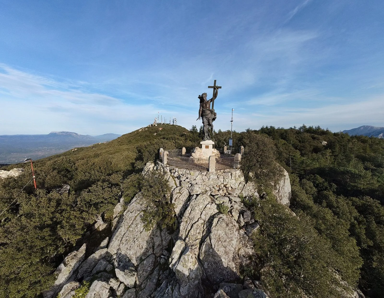 La statua in bronzo del Redentore sulla vetta rocciosa del Monte Ortobene, circondata dal bosco